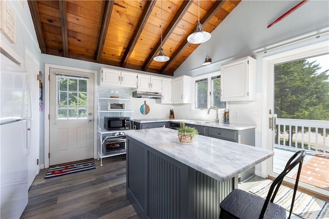 kitchen featuring under cabinet range hood, dark wood finished floors, lofted ceiling with beams, wooden ceiling, and white cabinetry