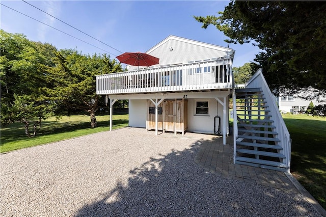 back of property featuring stairway, a lawn, and a wooden deck