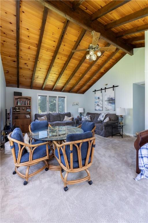 living area with lofted ceiling with beams, carpet, wood ceiling, and ceiling fan