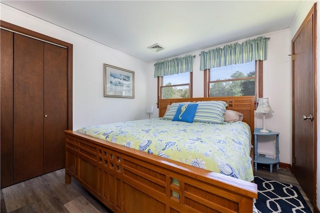 bedroom with dark wood-style floors, visible vents, and a closet