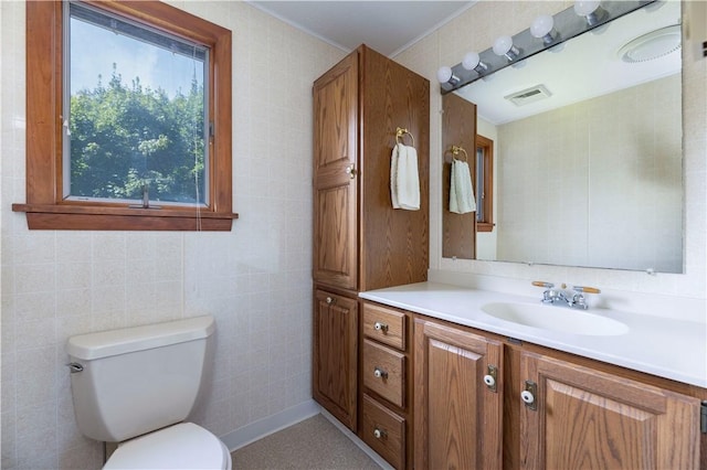 bathroom featuring visible vents, vanity, toilet, and tile walls