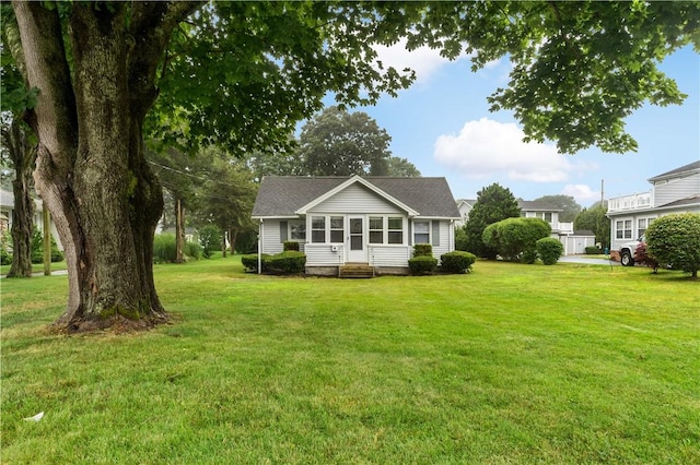 back of property featuring entry steps, a yard, and a sunroom