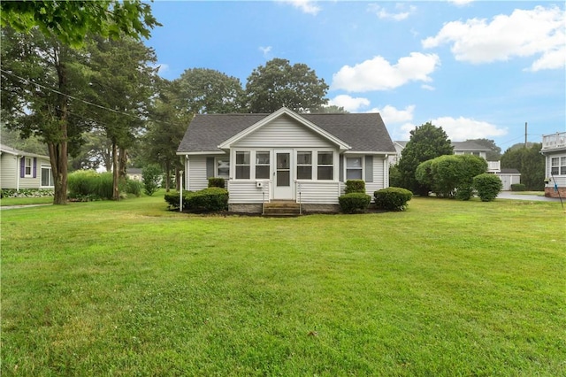 view of front of home with entry steps, a front yard, and roof with shingles