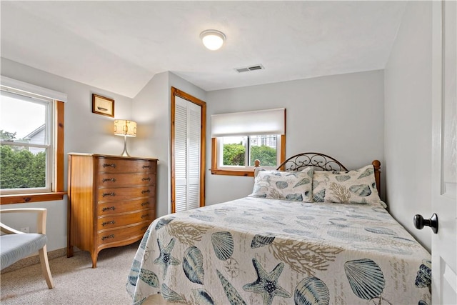 bedroom with a closet, visible vents, and light colored carpet