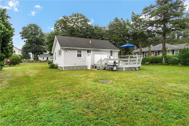 rear view of house featuring a lawn, roof with shingles, and a wooden deck