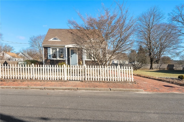 view of front of house with a fenced front yard and roof with shingles