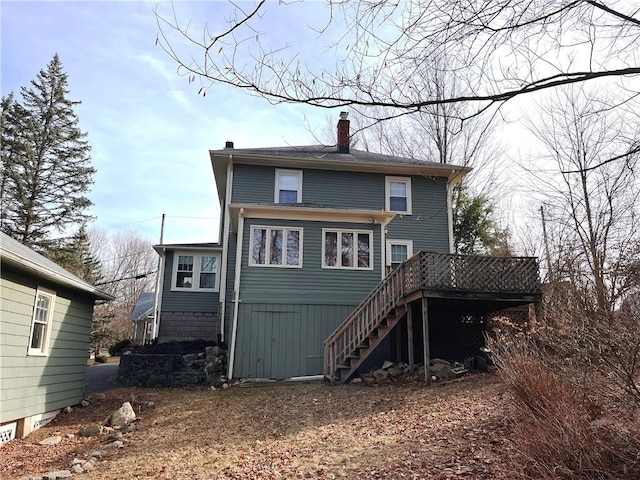 rear view of house with a wooden deck, stairway, and a chimney