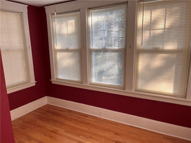 unfurnished dining area with wood finished floors and baseboards