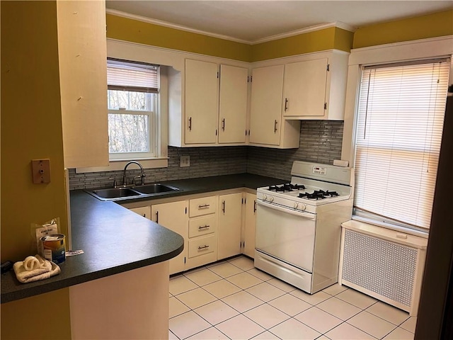 kitchen with dark countertops, radiator, white range with gas stovetop, ornamental molding, and a sink