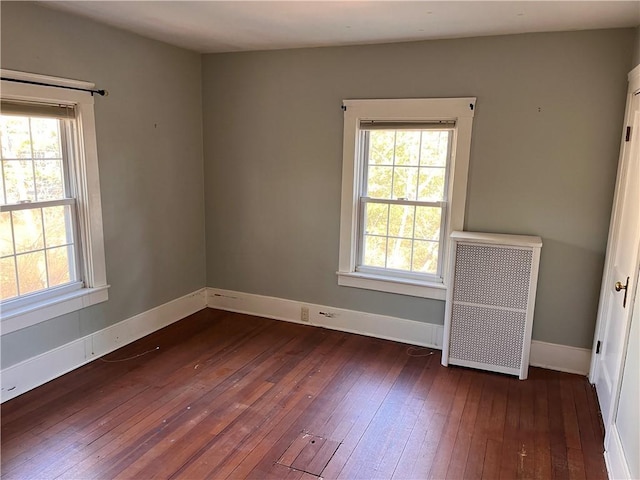 spare room with radiator, baseboards, and dark wood-style flooring