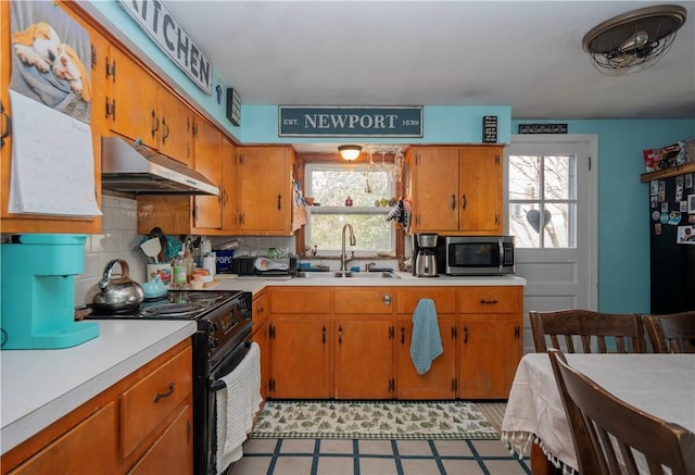 kitchen featuring stainless steel microwave, under cabinet range hood, light countertops, electric range, and a sink