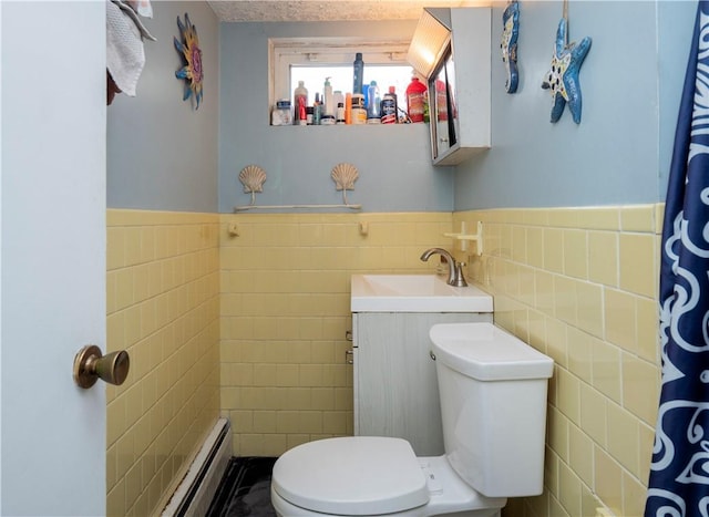 bathroom featuring a wainscoted wall, toilet, tile walls, baseboard heating, and vanity