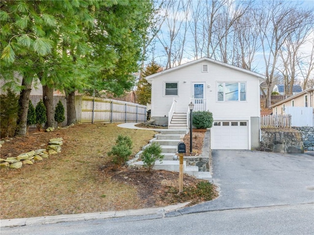 view of front of house with an attached garage, driveway, and fence