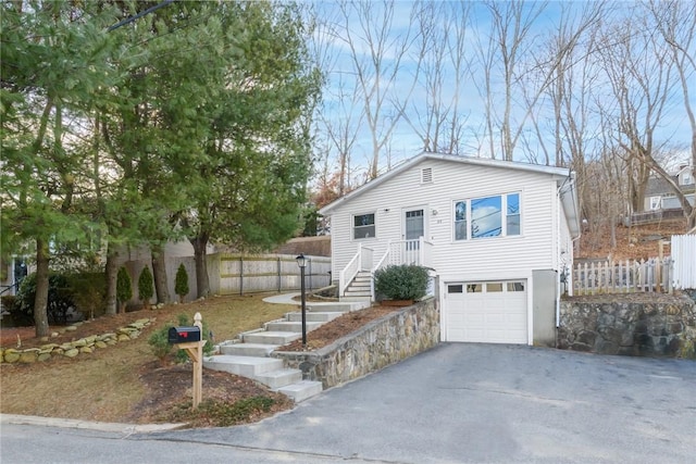 view of front of house featuring aphalt driveway, fence, and a garage