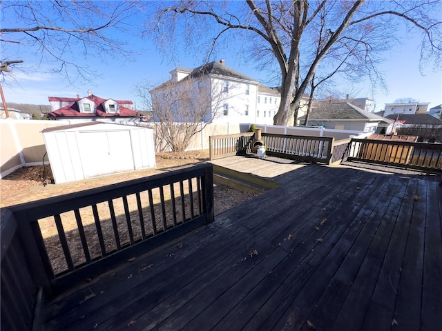 wooden deck featuring an outbuilding, a storage shed, and a fenced backyard