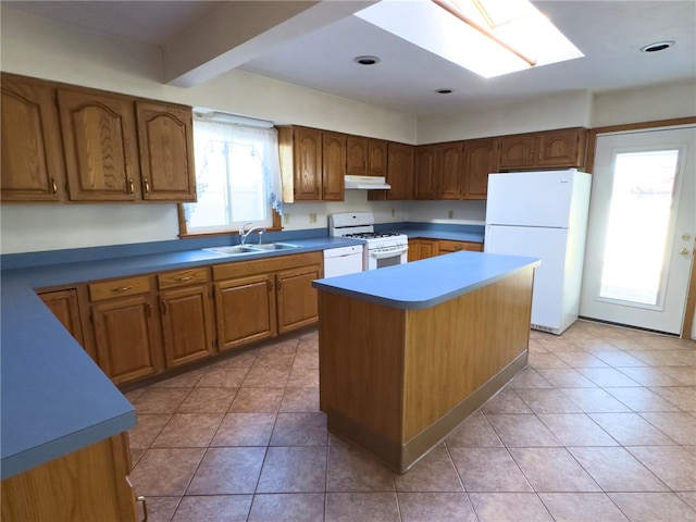 kitchen with a sink, under cabinet range hood, a kitchen island, white appliances, and a skylight