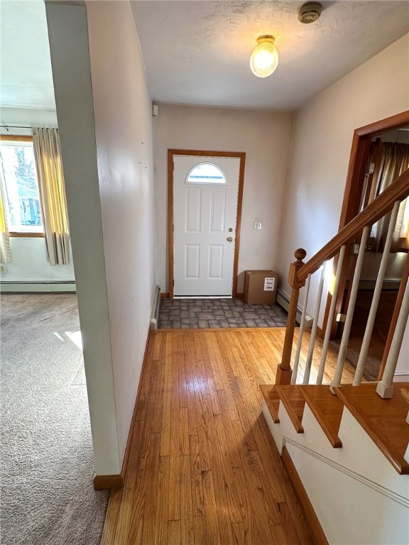 foyer entrance with a baseboard heating unit, hardwood / wood-style flooring, and stairs