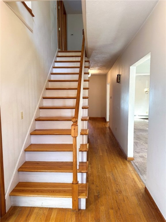 staircase featuring wood finished floors and baseboards