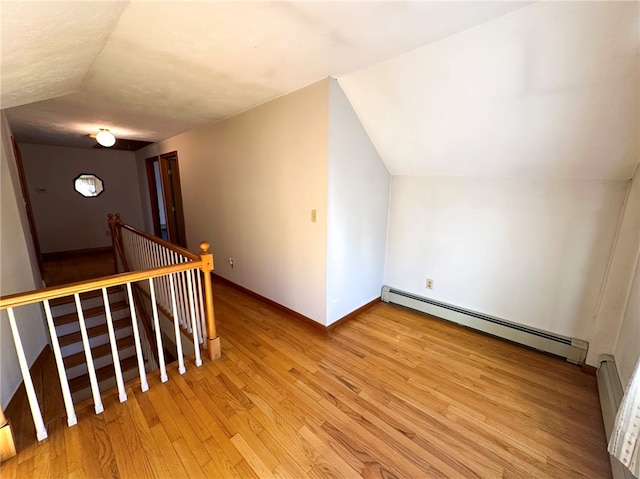 bonus room featuring vaulted ceiling, light wood-style floors, baseboards, and a baseboard radiator