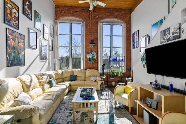 living room with ceiling fan, a high ceiling, brick wall, and wooden ceiling