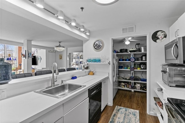 kitchen featuring visible vents, a sink, stainless steel appliances, light countertops, and dark wood-style flooring