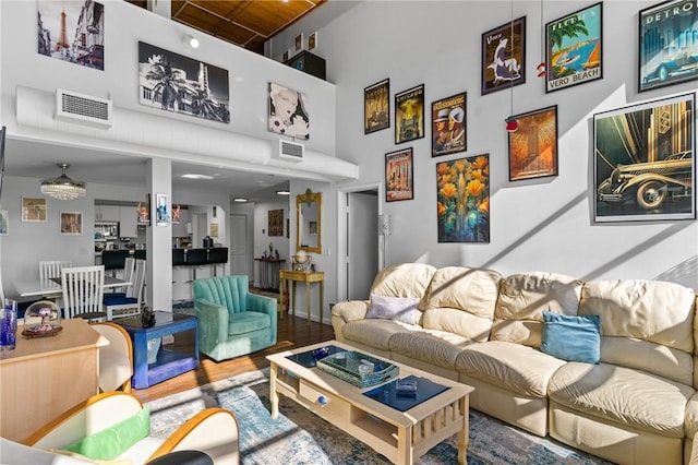 living area with visible vents, a high ceiling, and wood finished floors