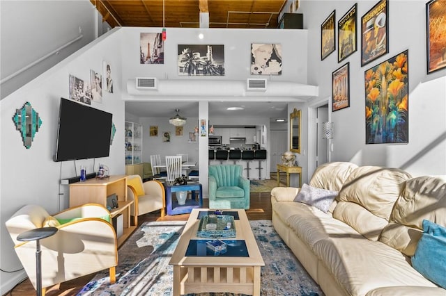 living area with visible vents, a towering ceiling, and wood finished floors