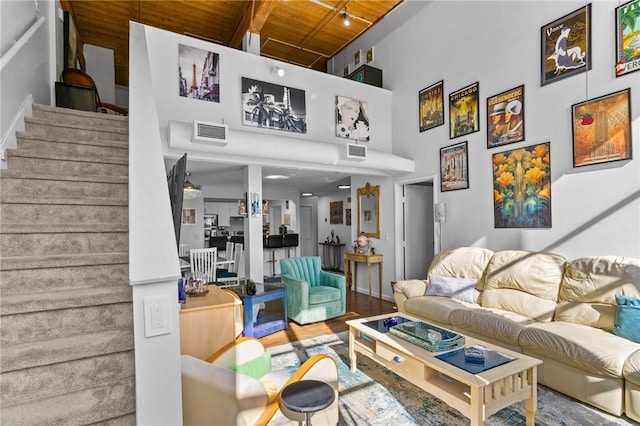 living area with visible vents, wood finished floors, a towering ceiling, and stairs