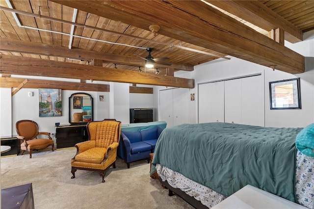 bedroom with beamed ceiling, wooden ceiling, two closets, and carpet