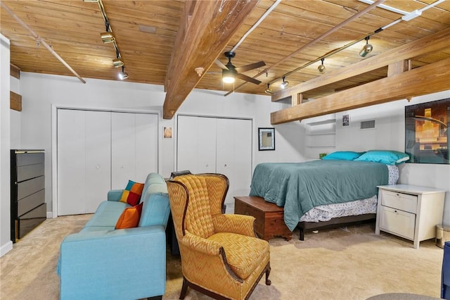 bedroom featuring light carpet, rail lighting, two closets, and wood ceiling