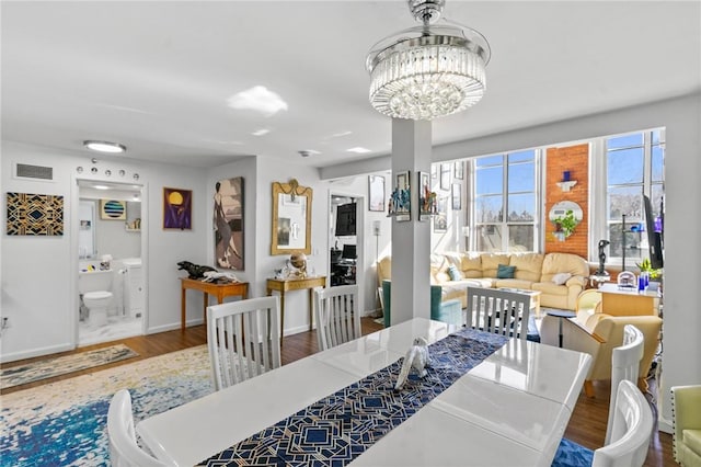 dining space featuring visible vents, baseboards, a notable chandelier, and wood finished floors