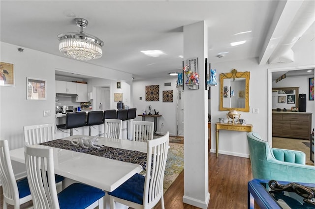 dining space with baseboards, an inviting chandelier, and wood finished floors