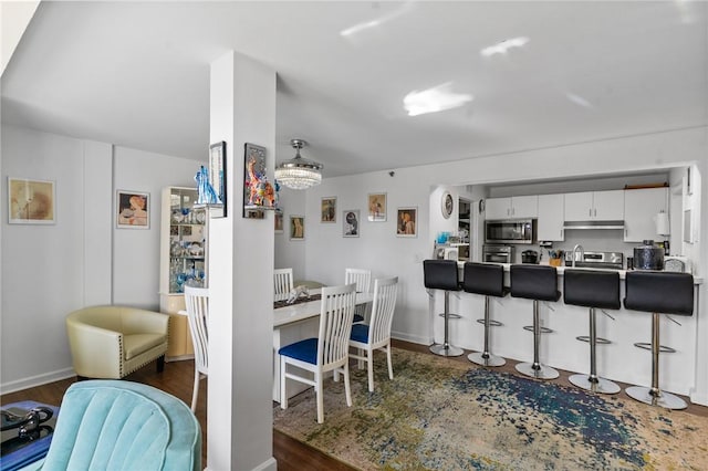 kitchen with a breakfast bar, stainless steel microwave, white cabinets, and under cabinet range hood