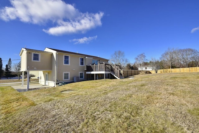 back of house featuring fence, a yard, stucco siding, stairs, and central air condition unit