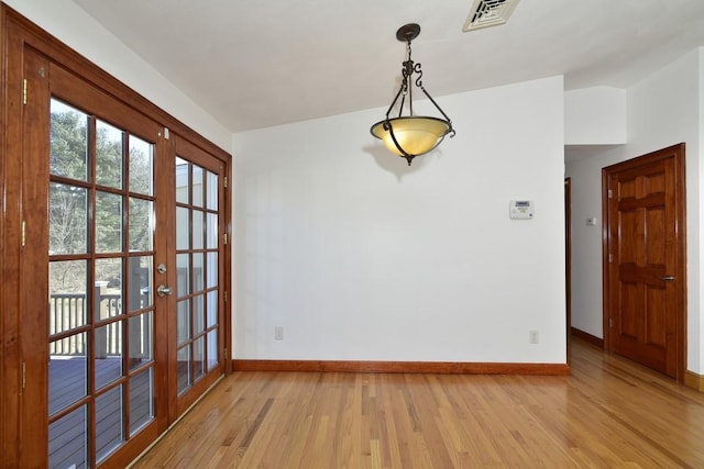 empty room featuring french doors, visible vents, light wood finished floors, and baseboards