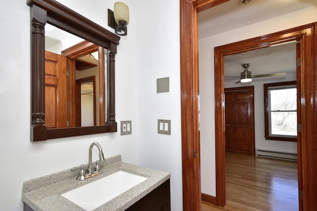 bathroom featuring vanity, wood finished floors, baseboard heating, and ceiling fan