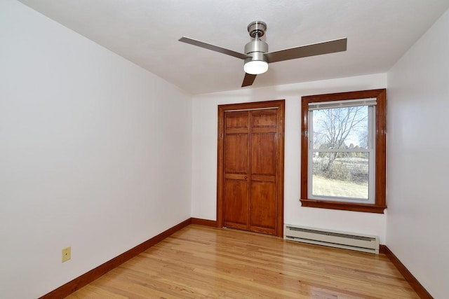 unfurnished bedroom with light wood-type flooring, baseboards, baseboard heating, and a closet