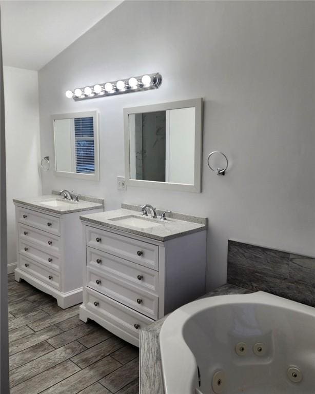 full bathroom featuring a sink, lofted ceiling, two vanities, and wood finished floors