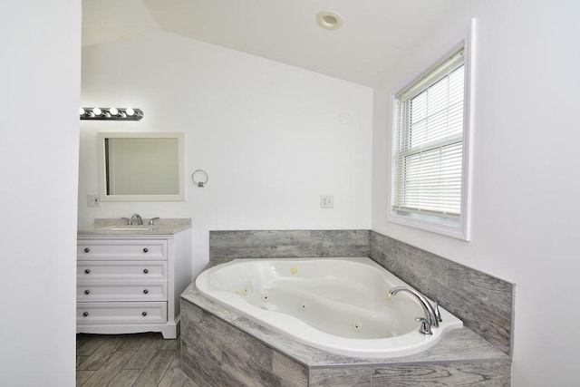 bathroom with vanity, vaulted ceiling, and a tub with jets