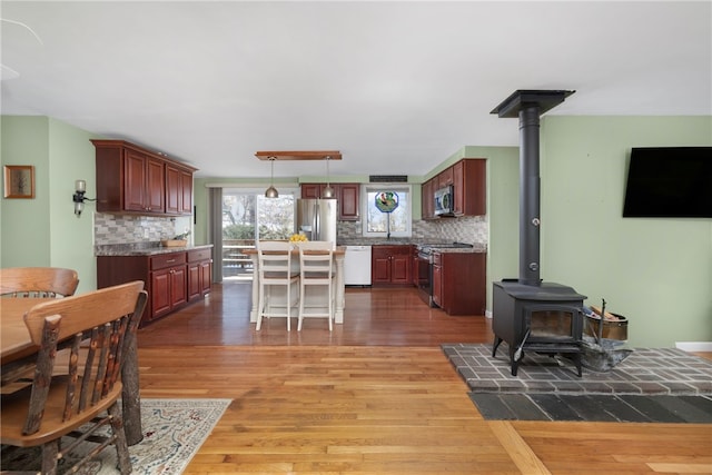 dining space featuring a wood stove and light wood-style flooring