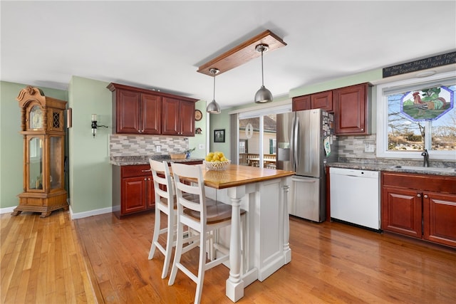 kitchen featuring light wood finished floors, a sink, stainless steel fridge with ice dispenser, and white dishwasher