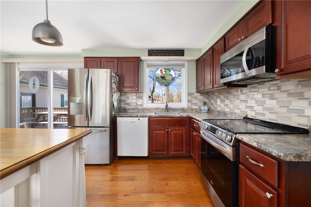 kitchen featuring light wood-type flooring, stainless steel appliances, backsplash, and a wealth of natural light