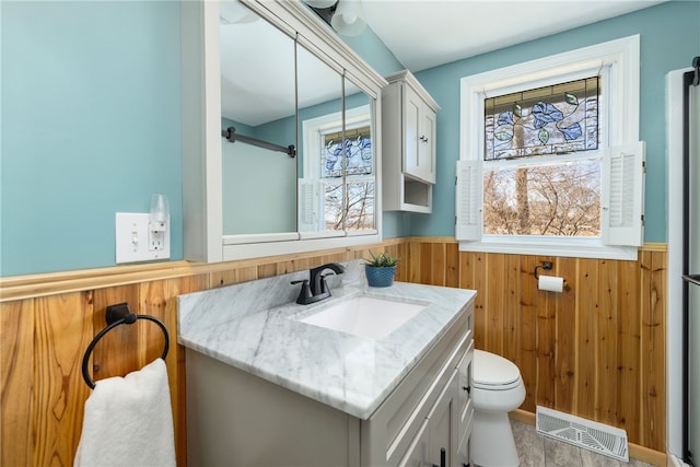 bathroom featuring wooden walls, visible vents, a wealth of natural light, and wainscoting