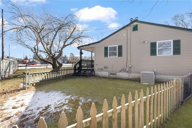 rear view of house featuring cooling unit, a lawn, and a fenced front yard