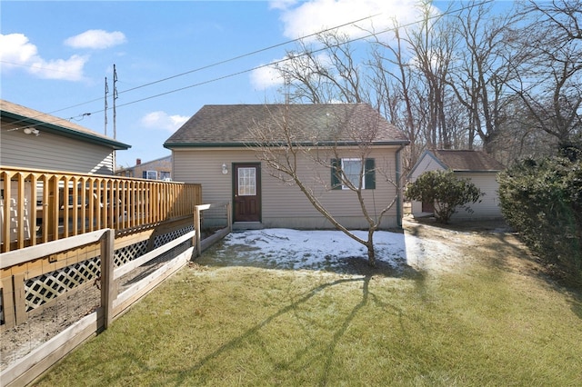 rear view of house featuring a lawn, roof with shingles, and a deck