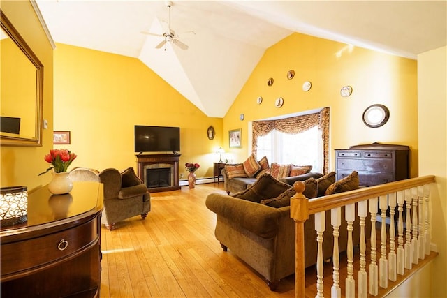 living area featuring light wood finished floors, baseboard heating, a fireplace, high vaulted ceiling, and a ceiling fan