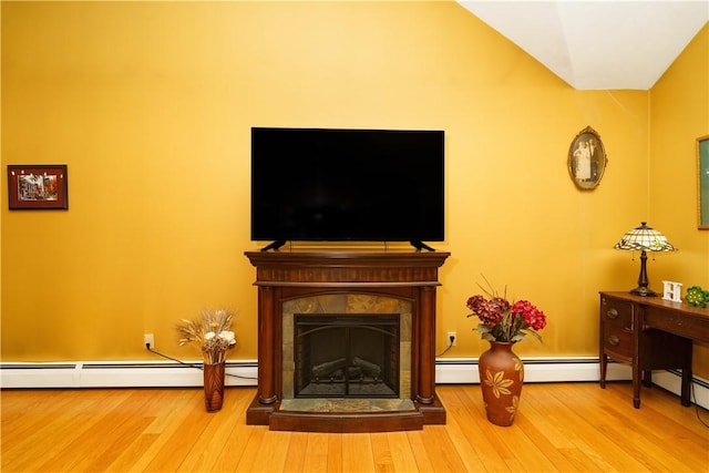 living area featuring wood finished floors, baseboard heating, and a fireplace with raised hearth