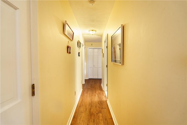 hallway featuring light wood finished floors and baseboards