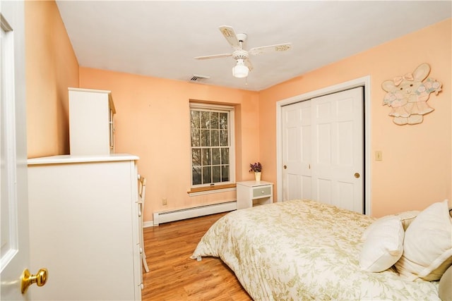 bedroom featuring visible vents, a ceiling fan, a closet, light wood finished floors, and baseboard heating