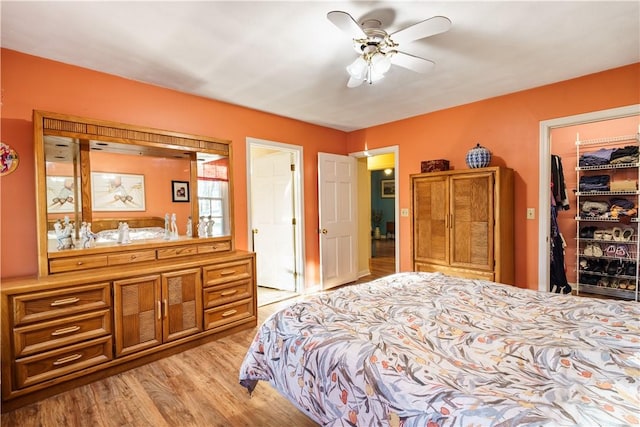 bedroom with light wood-style flooring, a spacious closet, and a ceiling fan